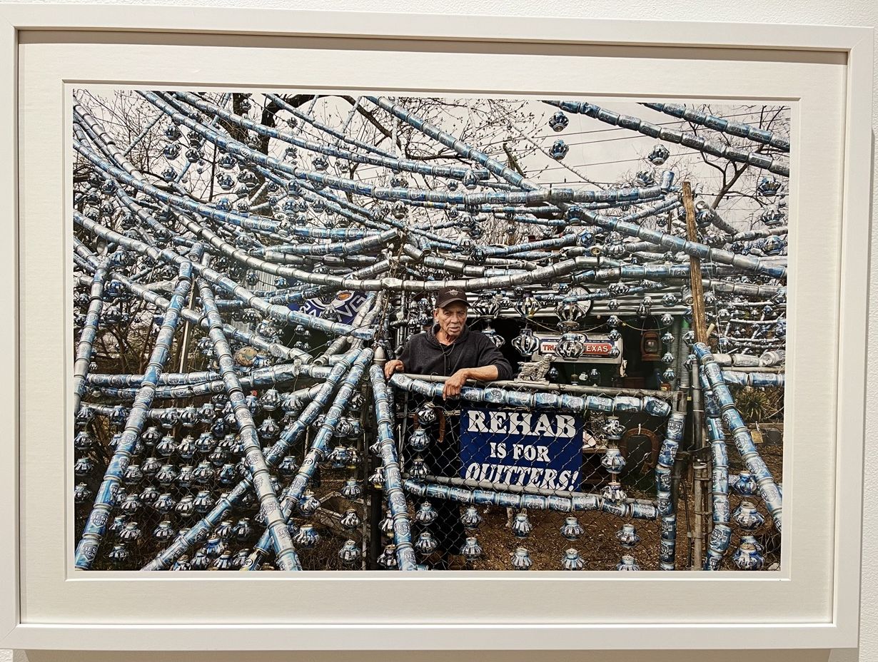 Man stands under his art environment made of beer cans