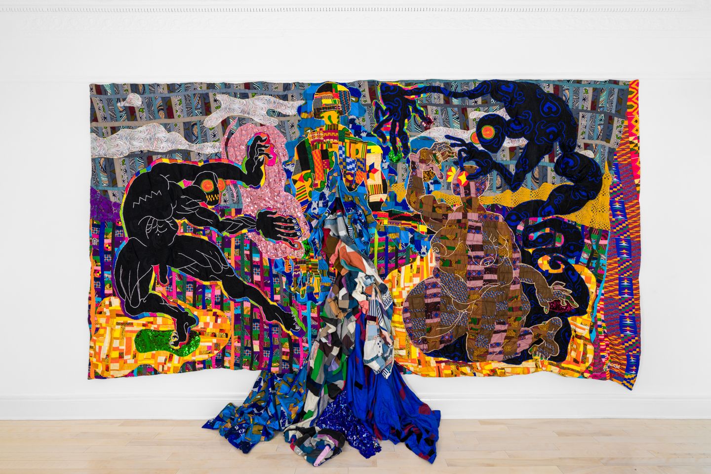 A-colorful-large-scale-quilt-with-multi-colored-nude-figures-and-a-three-dimensional-river,-flowing-onto-the-ground