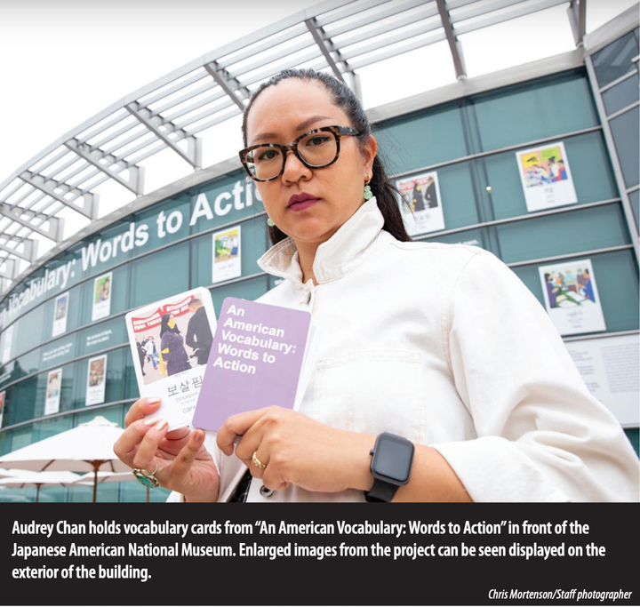 A close up image of a woman wearing glasses and a white jacket, holding two flash cards outside