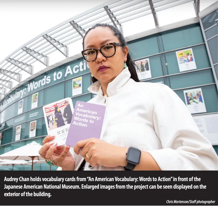 A close up image of a woman wearing glasses and a white jacket, holding two flash cards outside
